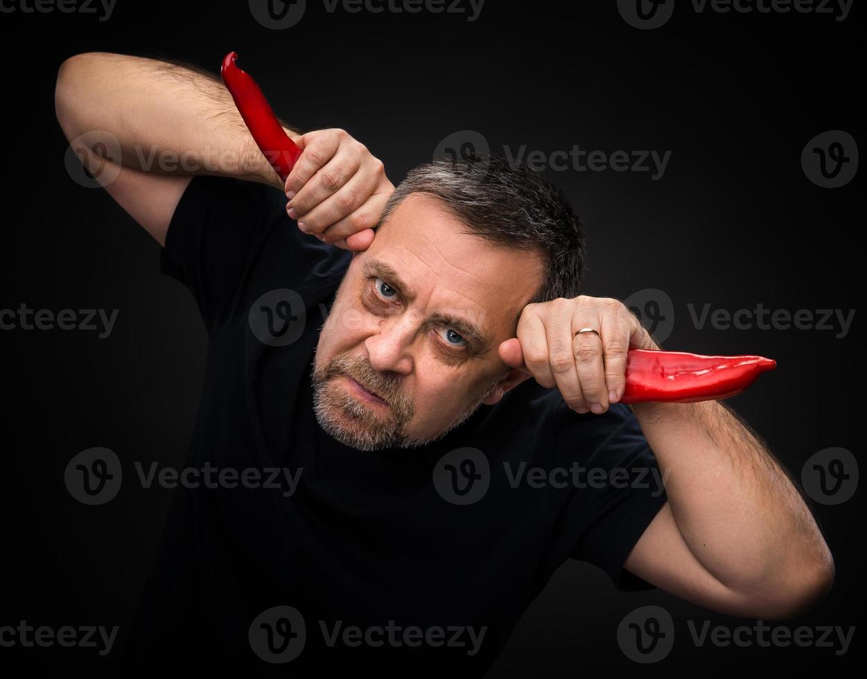 elderly man holding two red hot chili peppers photo