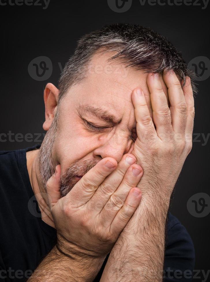 dolor de cabeza. hombre con la cara cerrada a mano foto