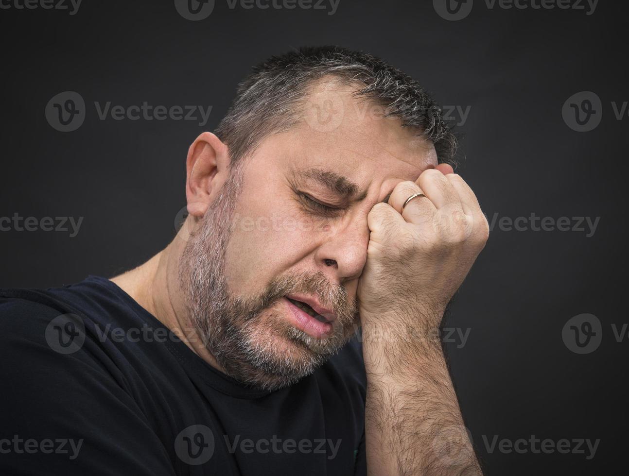 Headache. Man with face closed by hand photo