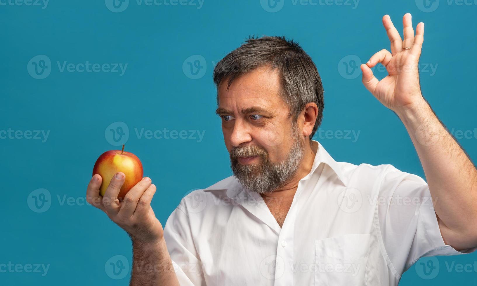 hombre de mediana edad sosteniendo una manzana roja foto