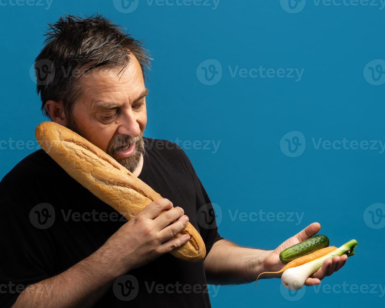 el hombre sostiene verduras en una mano y pan en la otra foto