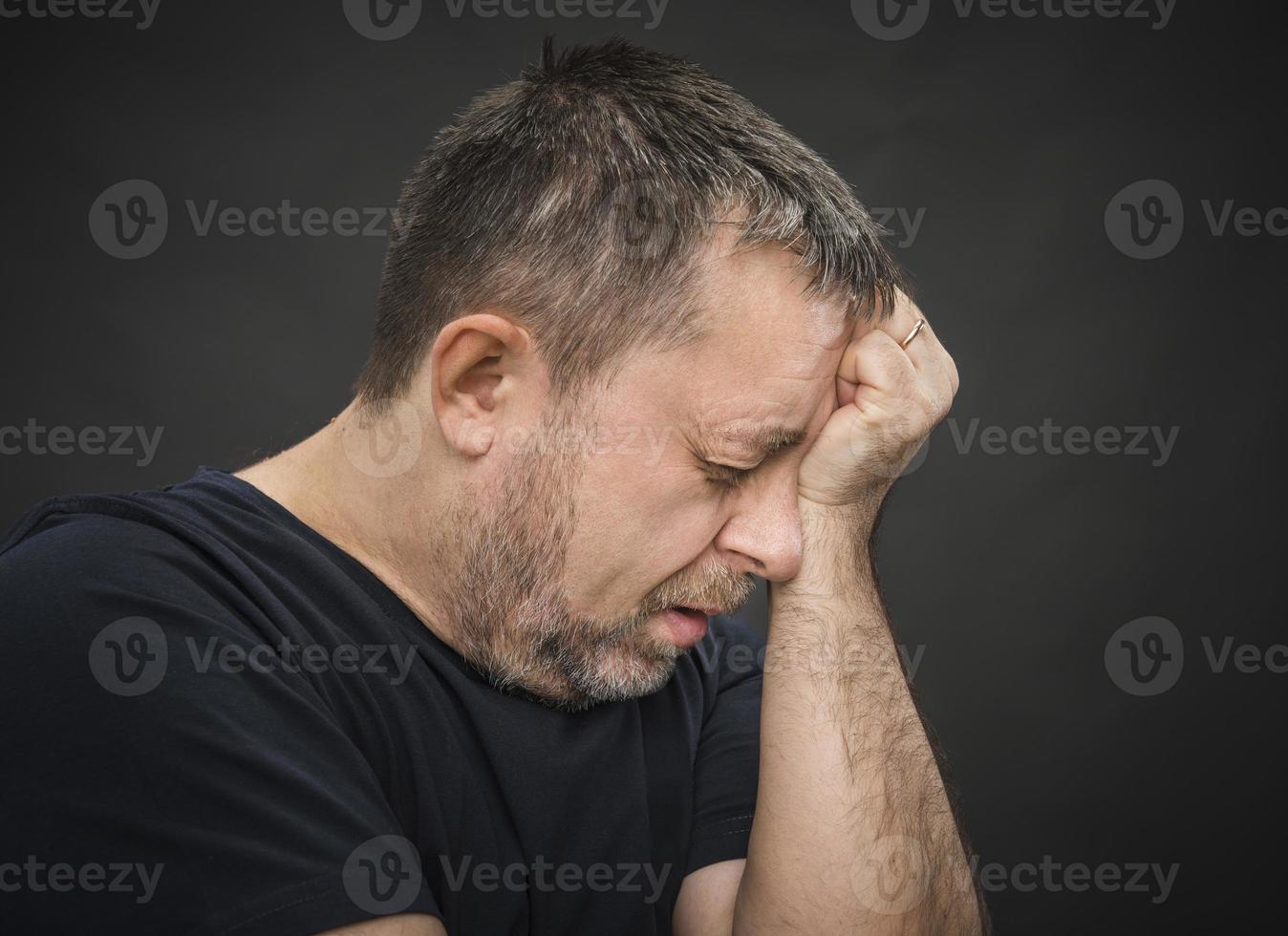 Headache. Man with face closed by hand photo