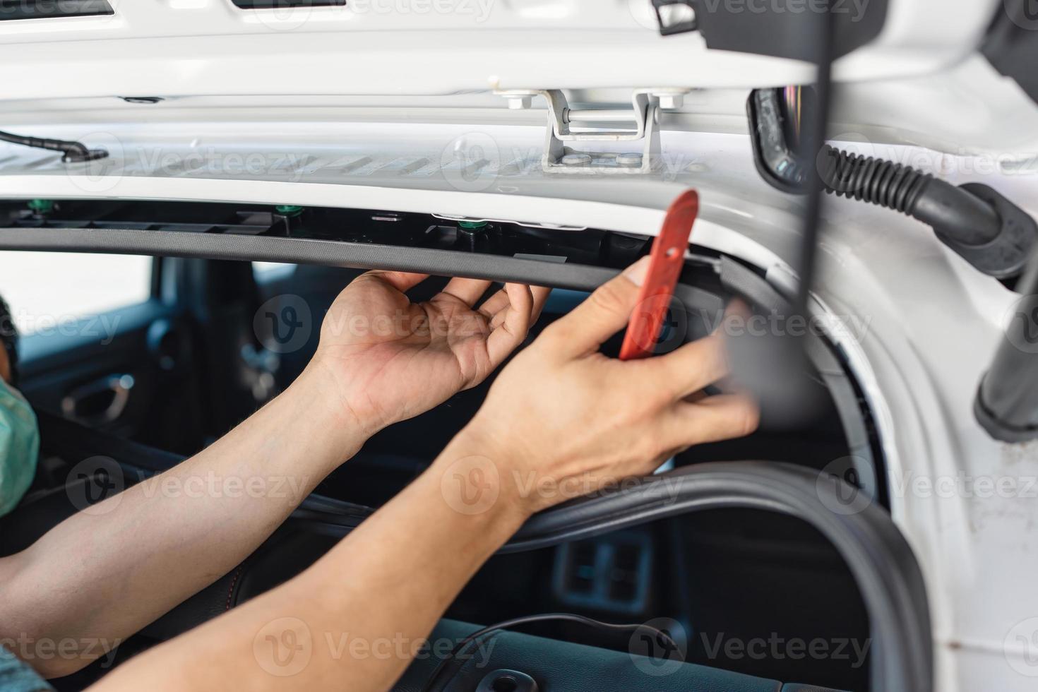Hand of mechanic using wedge removing and installing a dash cam inside