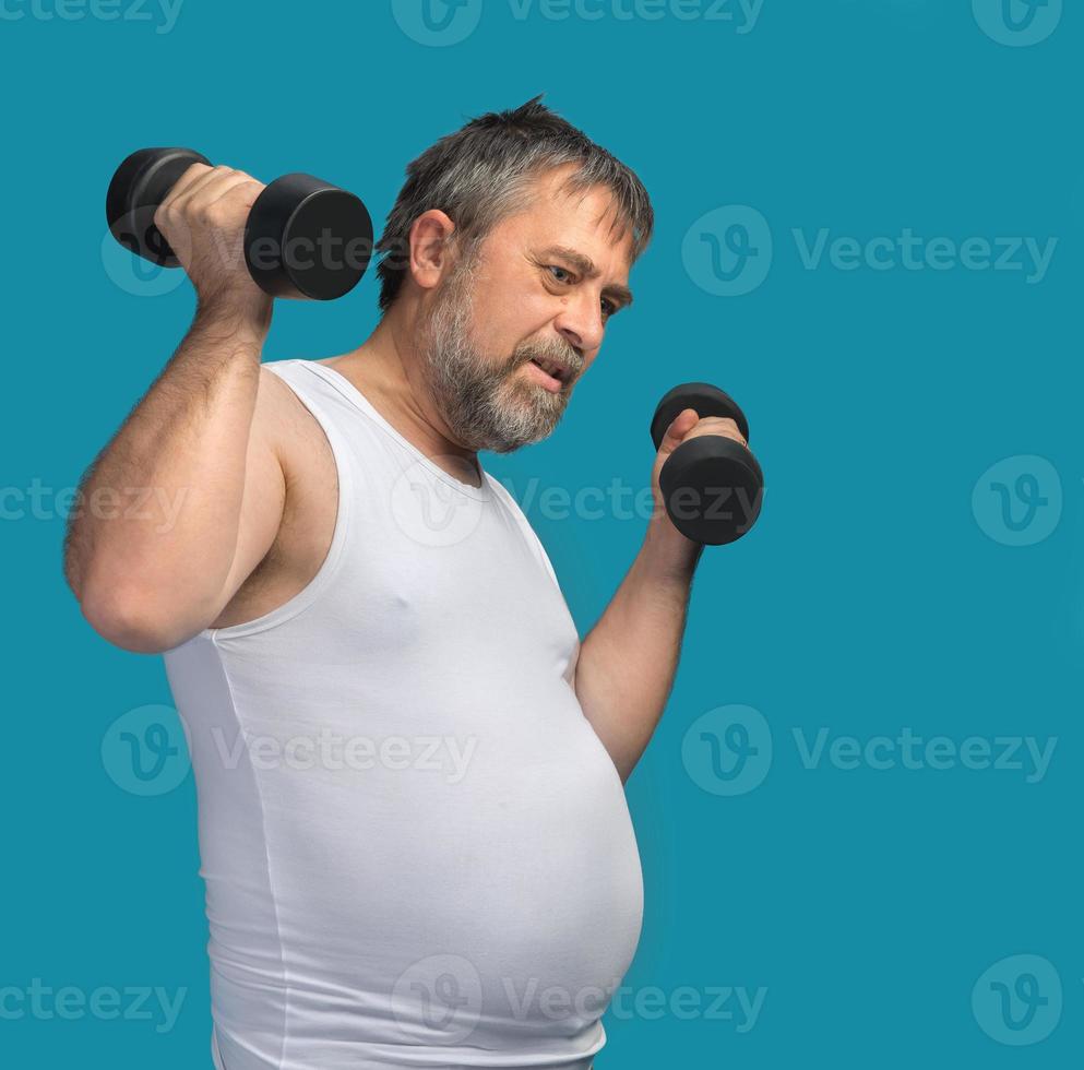 Fat middle-aged man exercising with dumbbells photo