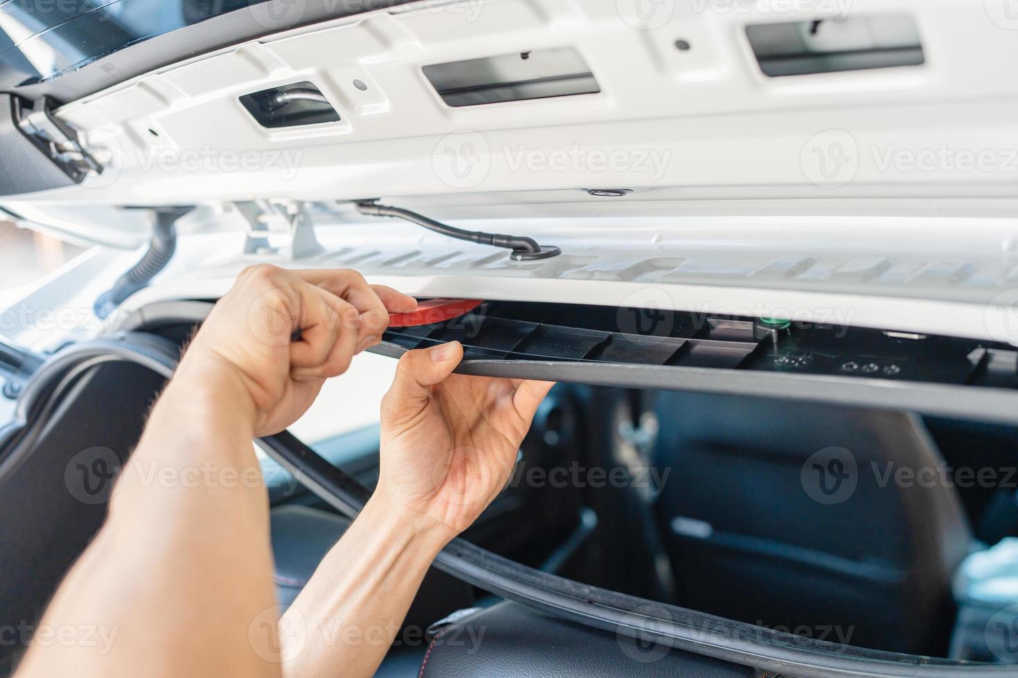 Hand of mechanic using wedge removing and installing a dash cam inside
