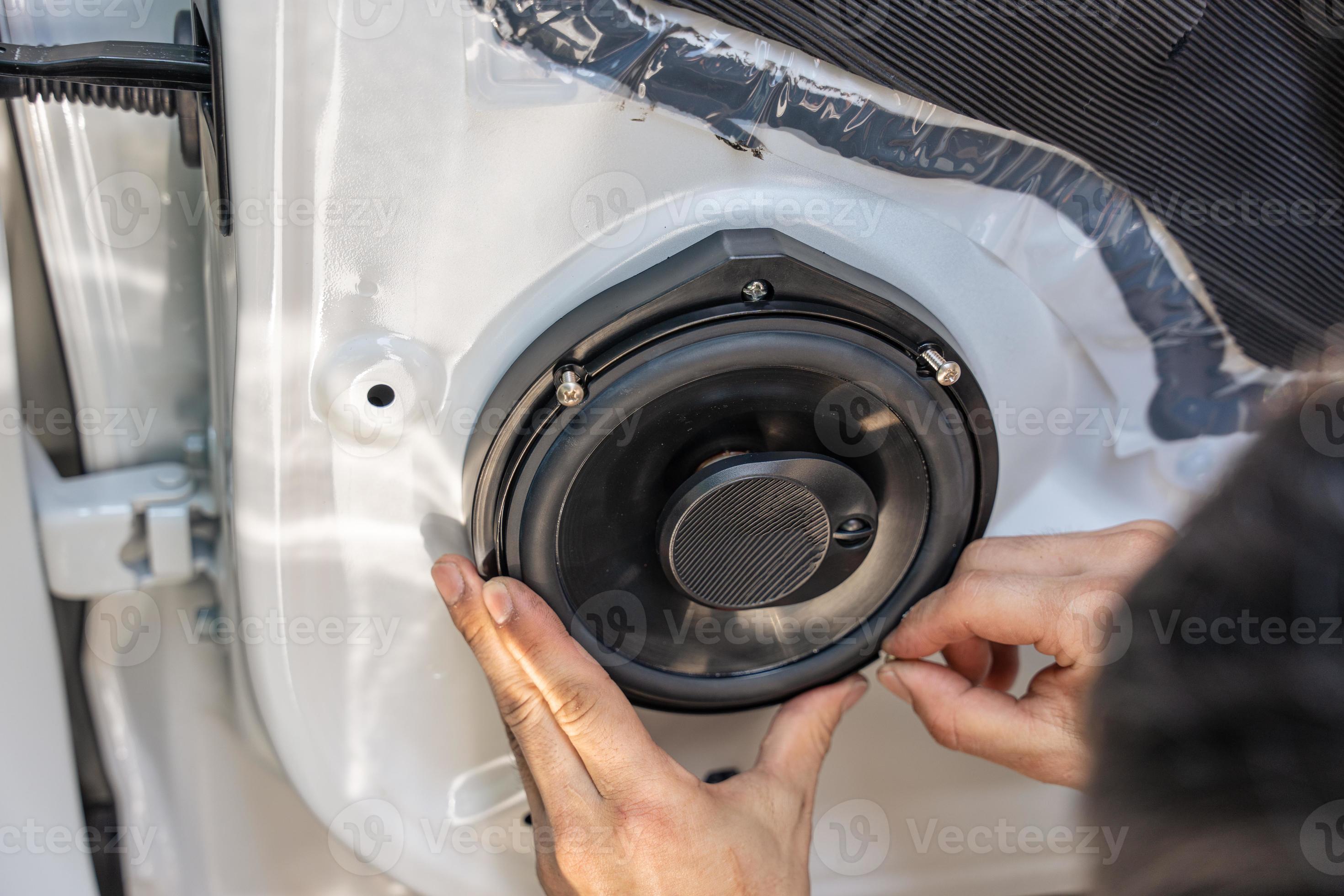 Mechanic man installing speaker on vehicle door part in garage 18727009