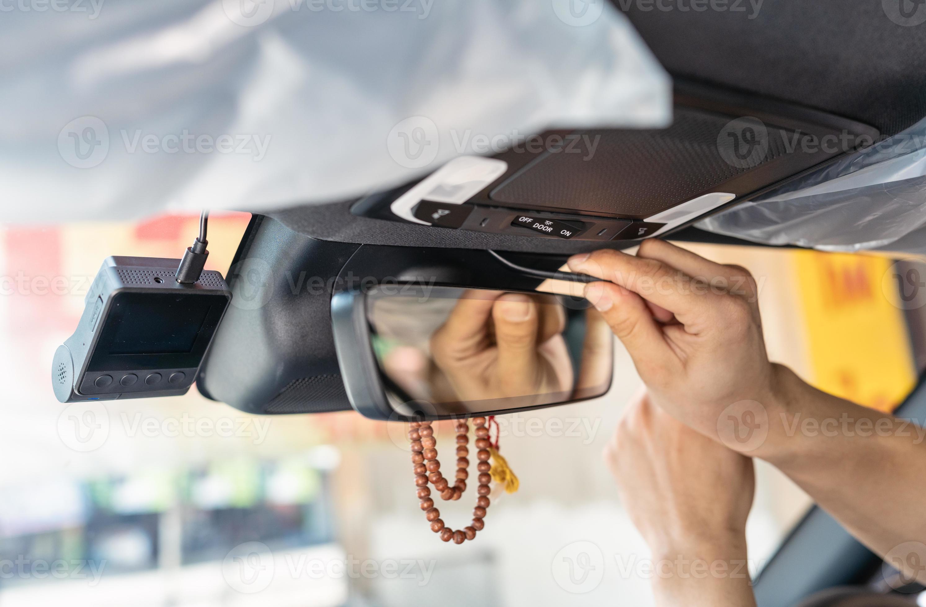 Hand of mechanic prying with installing a front camera car recorder