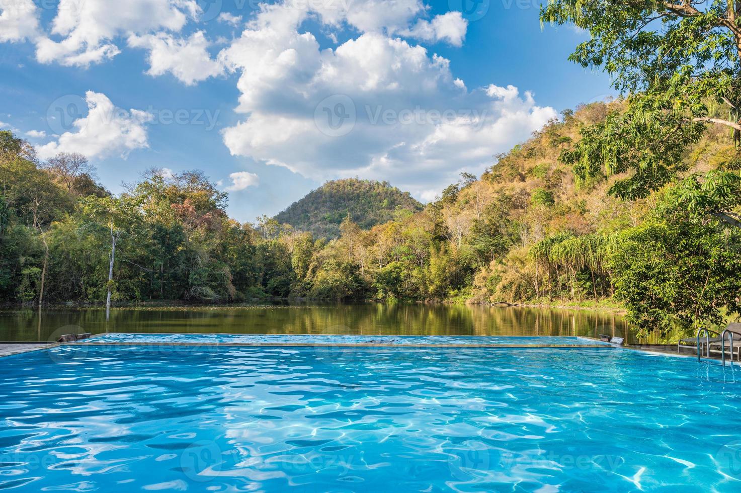 Swimming pool by the tropical rainforest on sunny day at the tropical resort photo