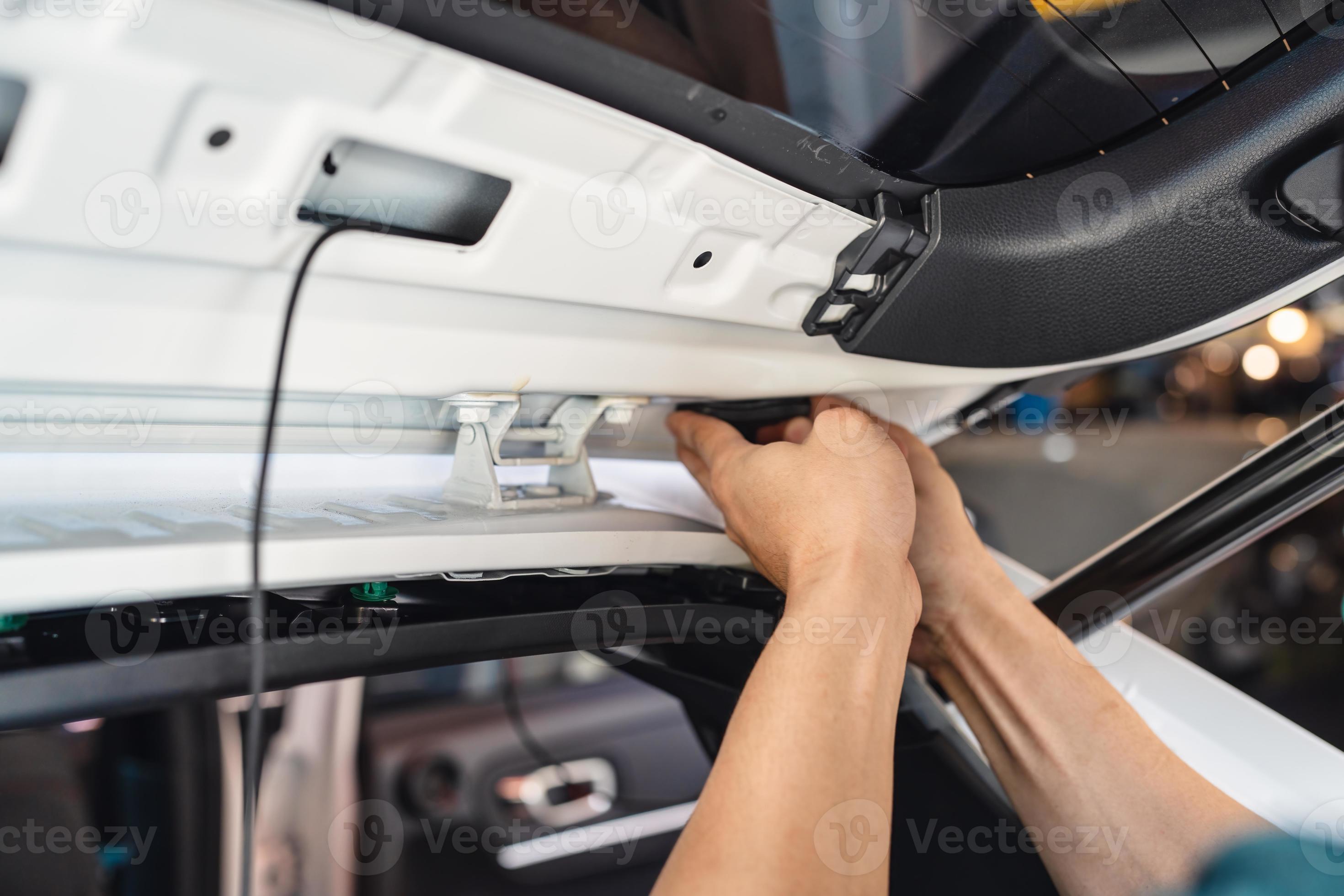 Hand of mechanic using wedge removing and installing a dash cam inside