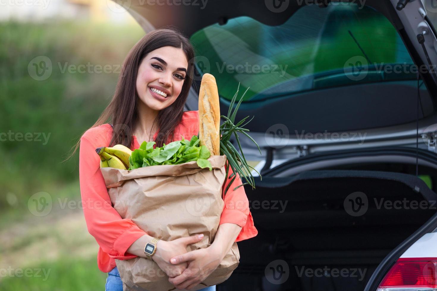 Close up portrait of a happy pretty girl holding bag with groceries and looking at camera with copy space. Close up of a woman holding heavy bag with groceries. Carrying a healthy bag photo