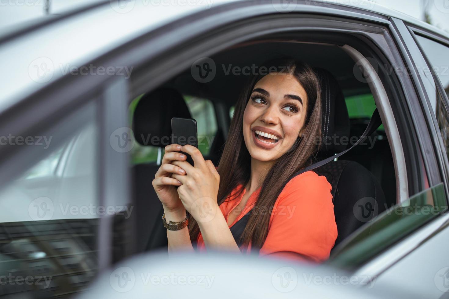 Nice beautiful young woman smile and use mobile phone touching the screen inside the car while travel. modern concept of search hings and contact friends when you are away. daily use of smartphone photo