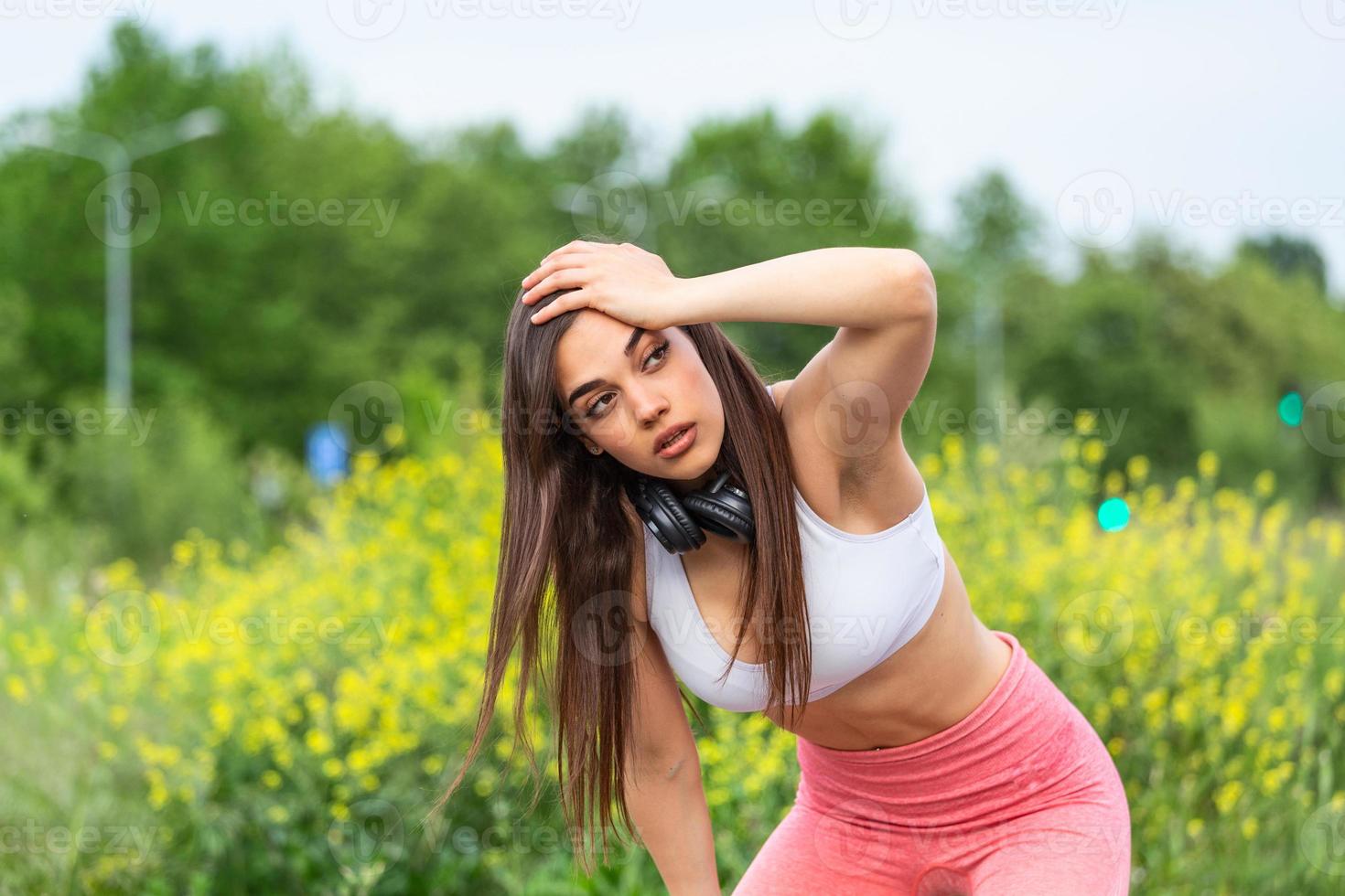 Tired young woman resting after jogging outdoor. Determined girl sweating and taking a rest after running hard. Exhausted curvy woman relaxing after running in park with breathing exercise. photo