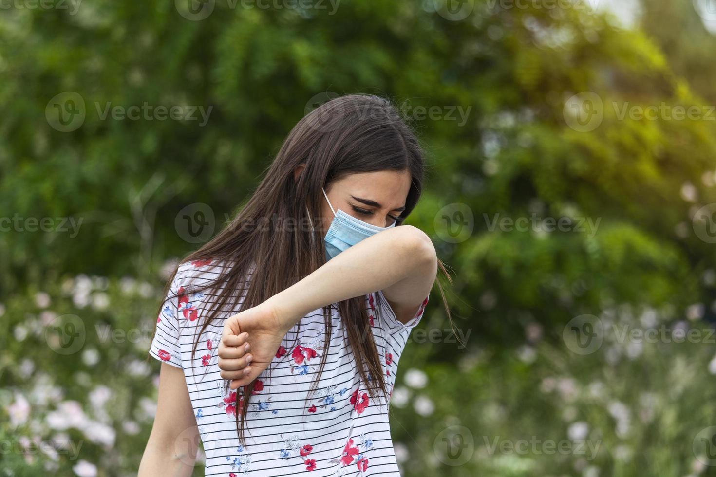 How to sneeze correctly. Woman with protective mask sneezes on the elbow. Concept of not spread of the virus. photo