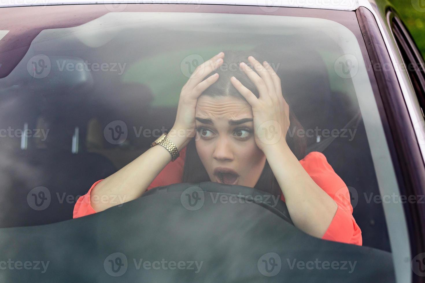 Stressed woman driver sitting inside her car. Angry female driver driving a car. Angry young woman stuck in a traffic jam. Woman annoyed in car. Girl stuck in traffic. photo