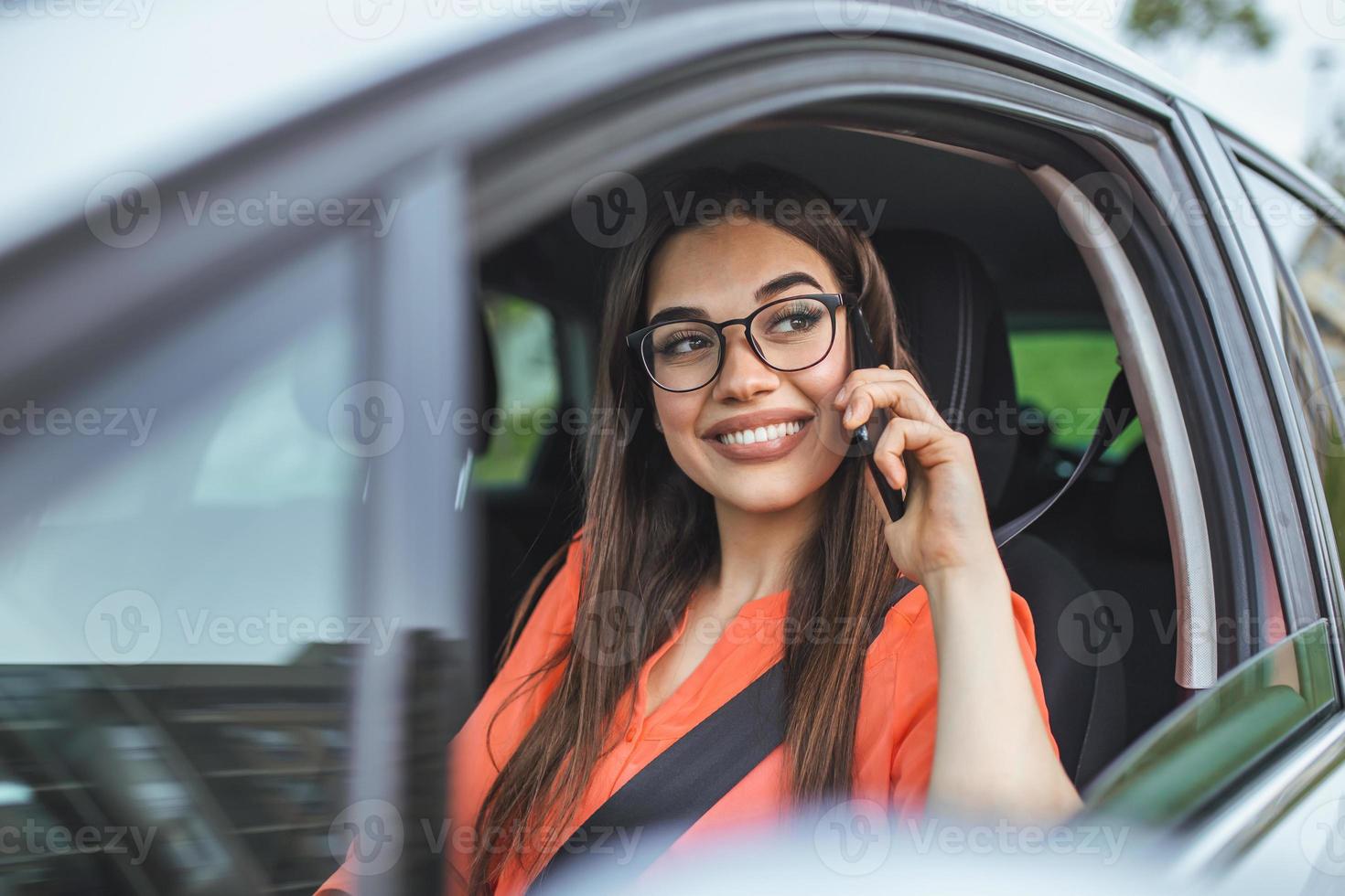 mujer de negocios conduciendo un coche y hablando por teléfono celular concentrándose en la carretera. conducir mientras se sostiene un teléfono móvil uso del teléfono celular mientras se conduce. mujer en coche hablando por teléfono móvil mientras conduce foto
