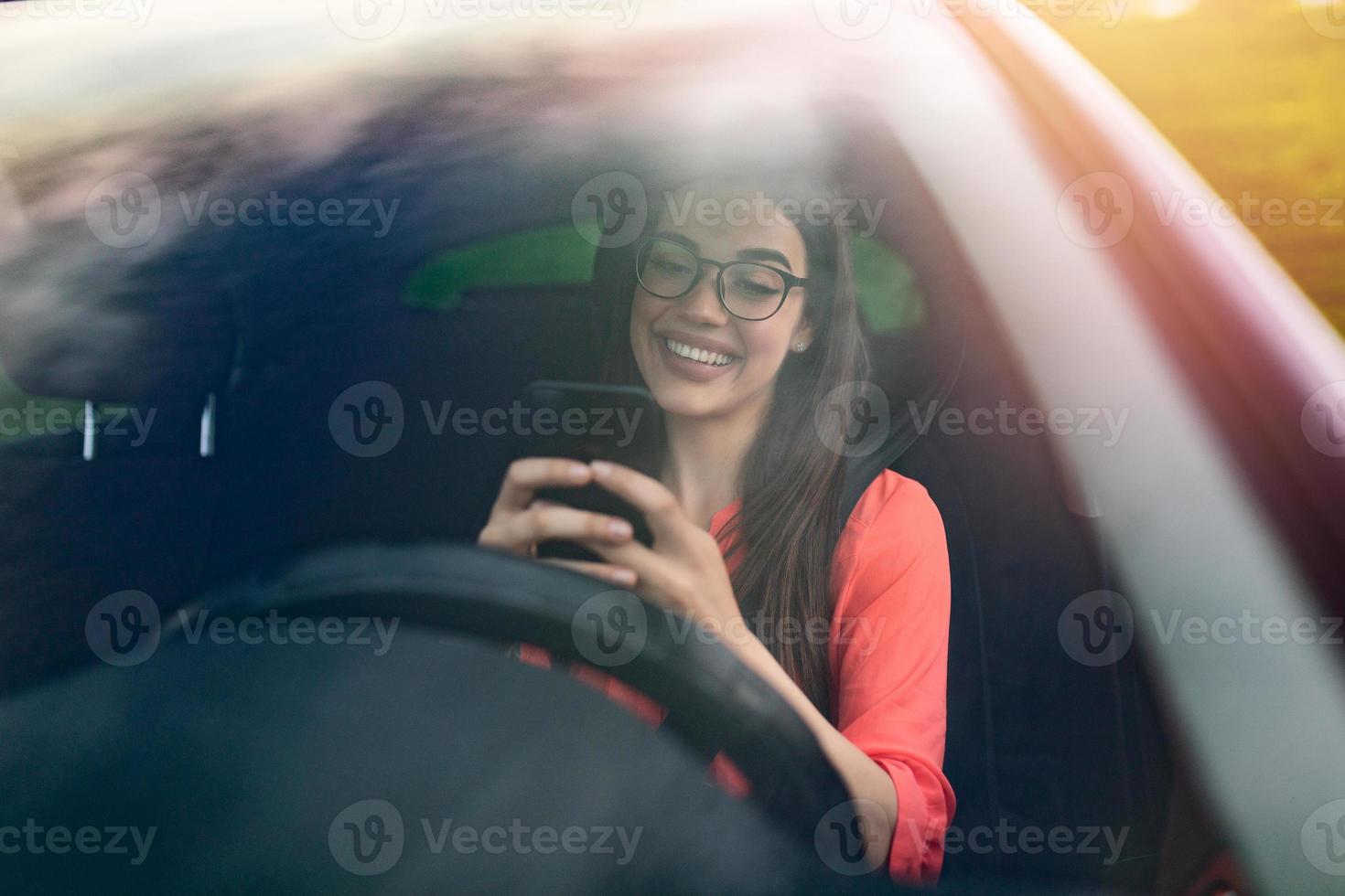 Texting and driving, behind the wheel. Breaking the law. Woman driving car distracted by her mobile phone. Woman typing message on the phone while waiting in the car. photo