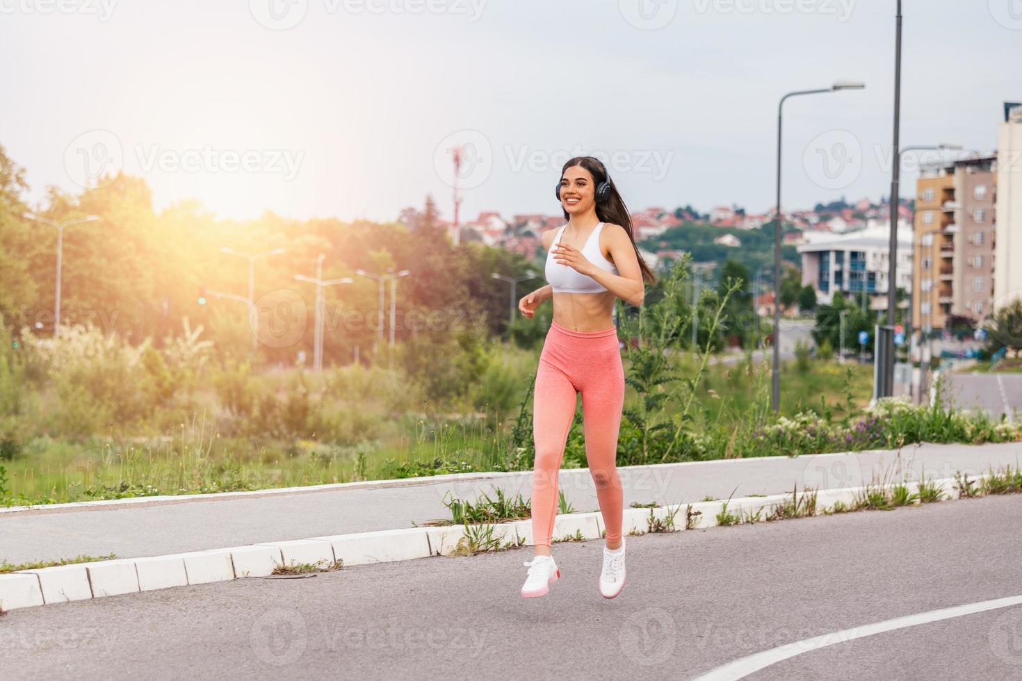 young attractive athletic woman speed running on city asphalt and workout in the morning time on a sunny summer day. Female runner training outdoor. Copyspace, sport concept photo