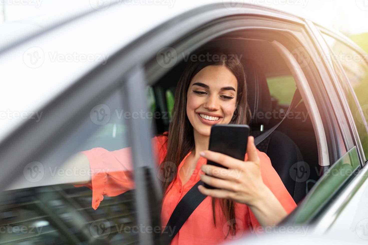 Nice beautiful young woman smile and use mobile phone touching the screen inside the car while travel. modern concept of search hings and contact friends when you are away. daily use of smartphone photo