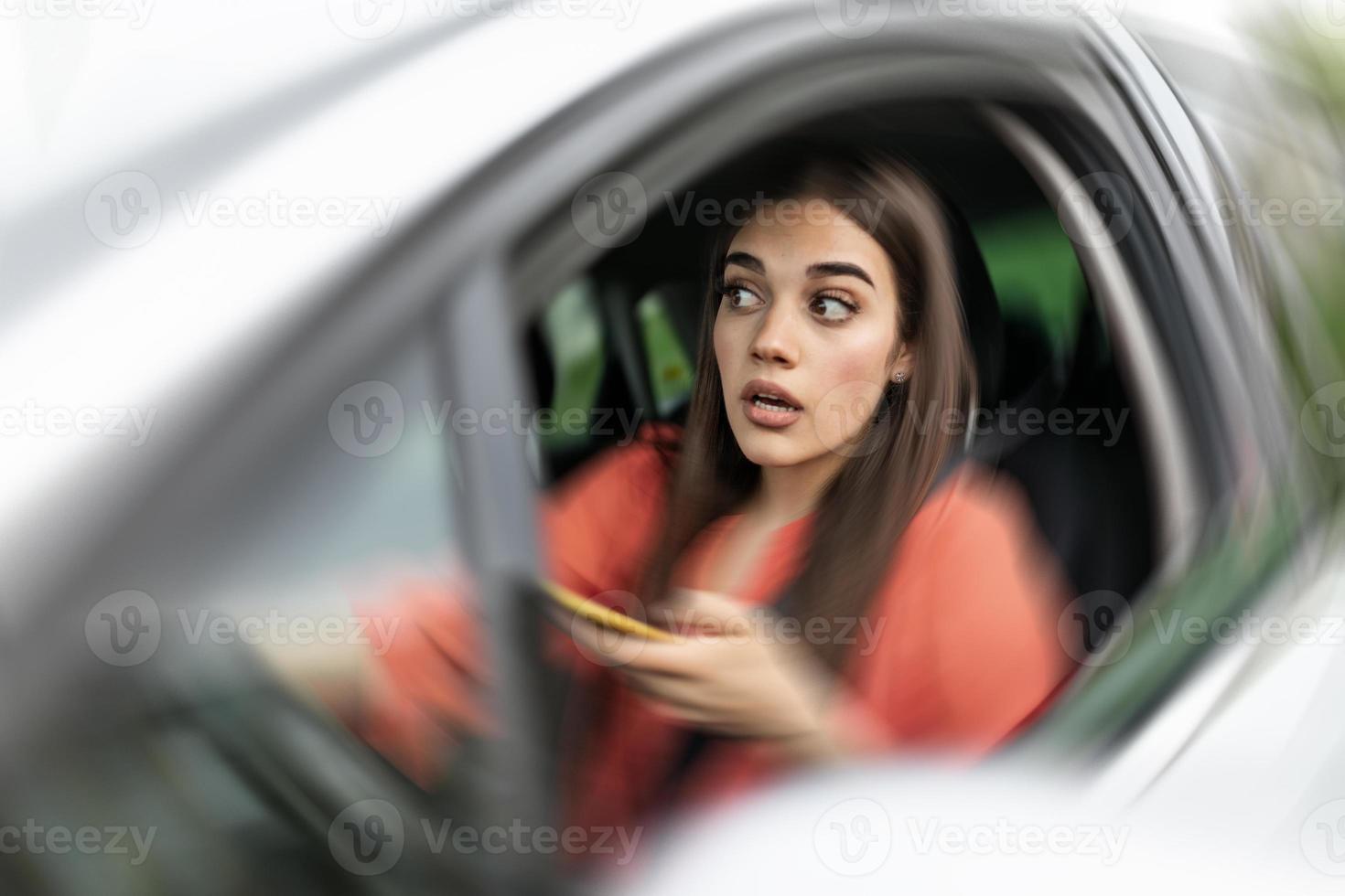 Texting and driving, behind the wheel. Breaking the law. Woman driving car distracted by her mobile phone causing an accident photo