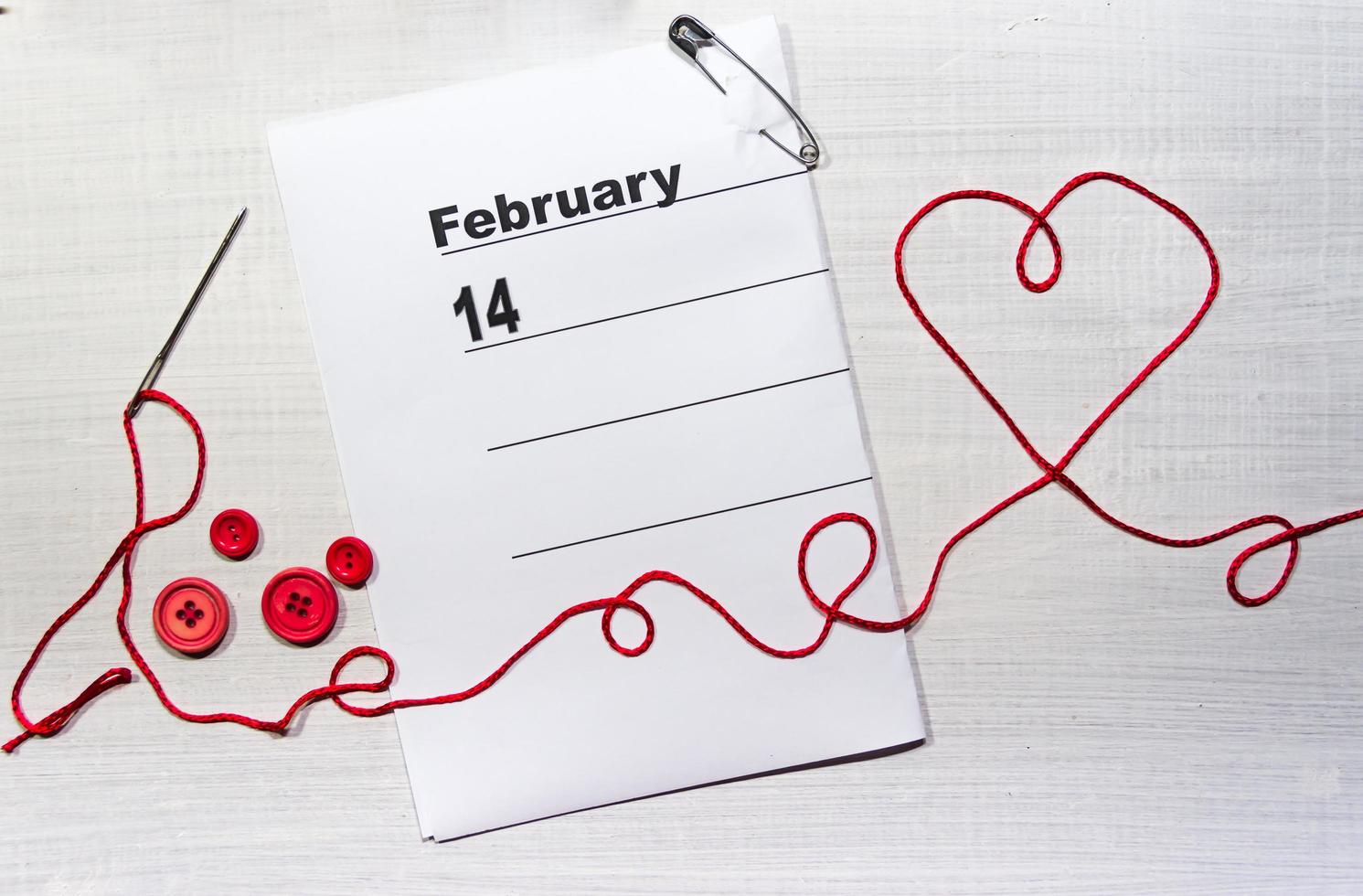 14 February calendar with heart of textile thread and buttons photo