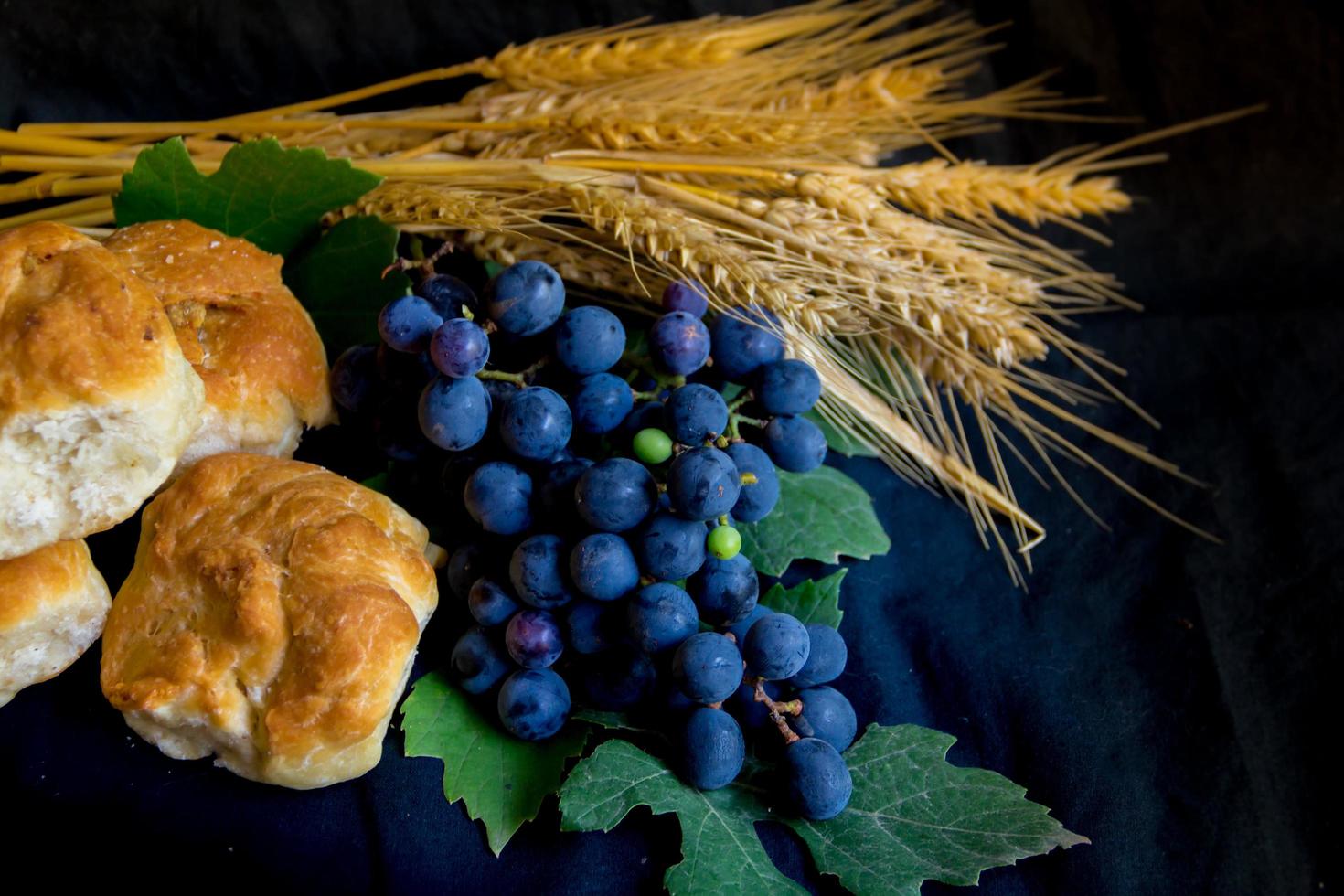 pan de uvas de trigo y corona de espinas sobre fondo negro como símbolo del cristianismo foto