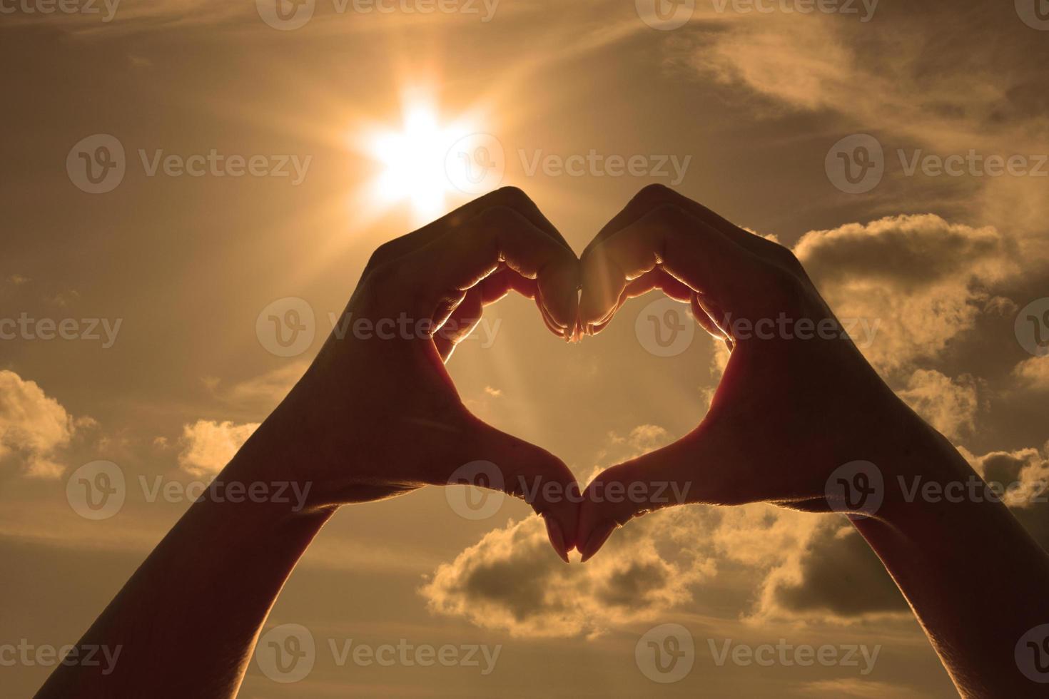 corazón en forma de mano contra la puesta de sol. concepto del día de san valentín foto