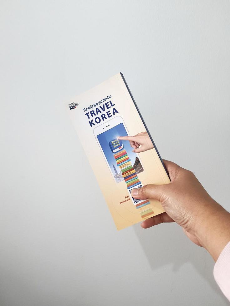 Jakarta, Indonesia in May 2022. A hand is holding a welcome guide book for travelers on vacation on Korea photo