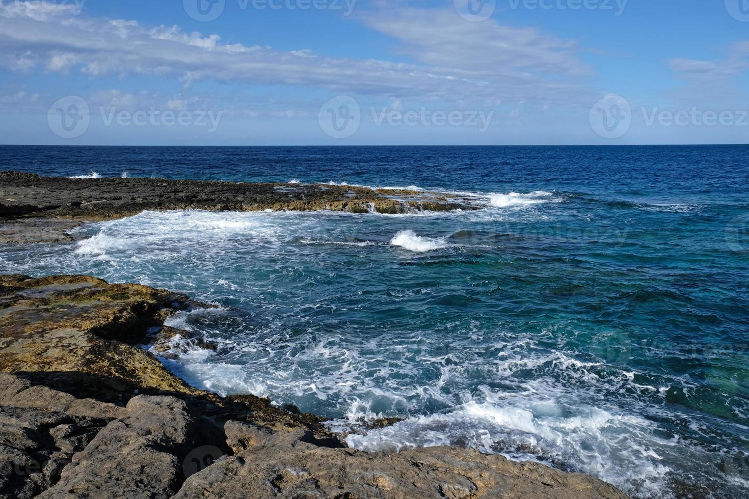 Blue sea wave and white foam. Stone beach on the island of Malta, no sandy beach. Summer holiday border frame concept. Tropical island vacation backdrop. Tourist travel banner design template. photo