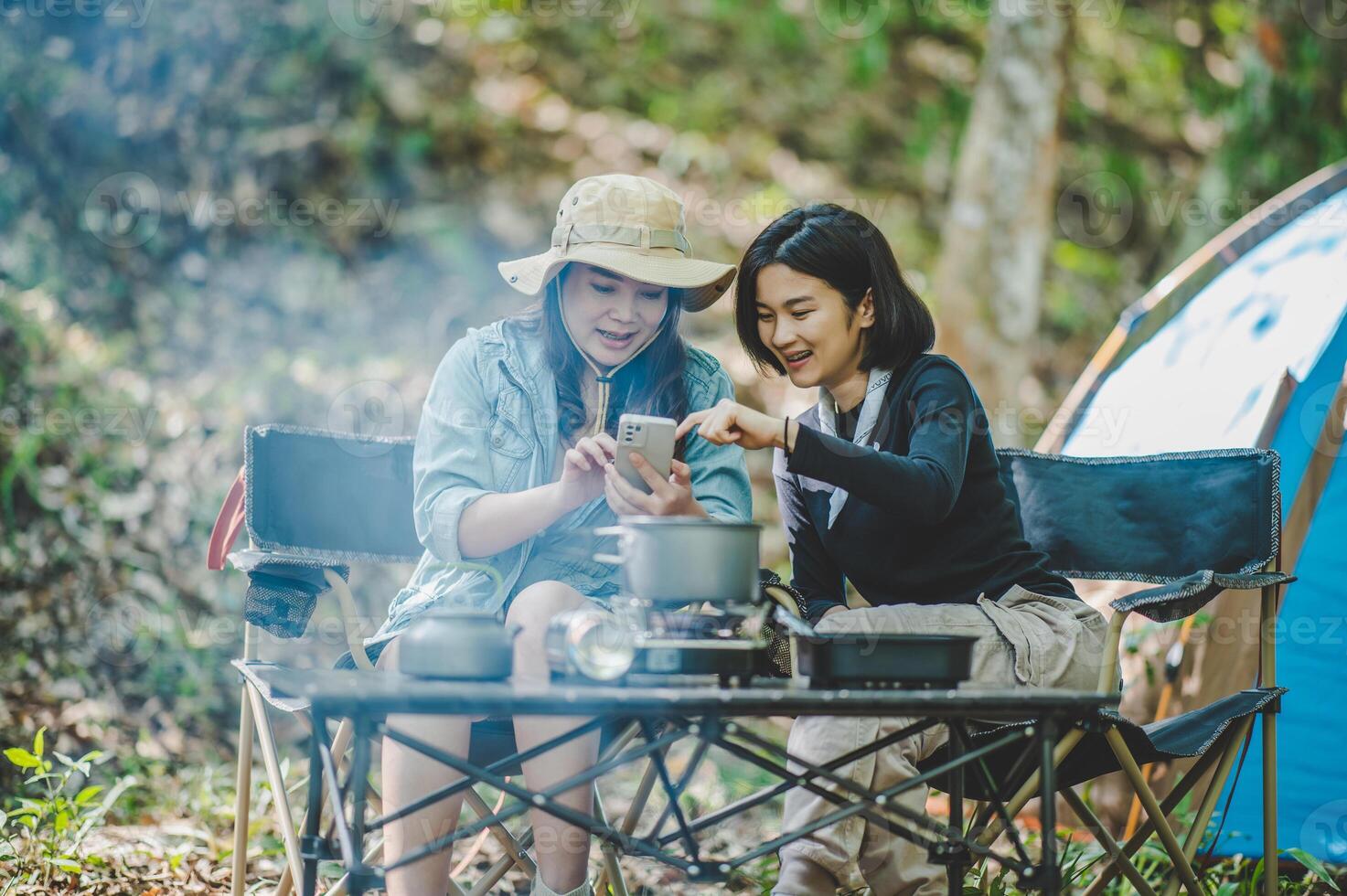 Asian pretty woman and friend use smartphone selfie on camping photo