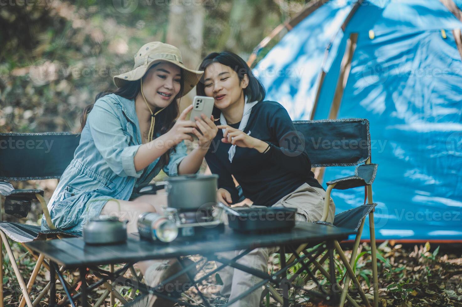 Asian pretty woman and friend use smartphone selfie on camping photo