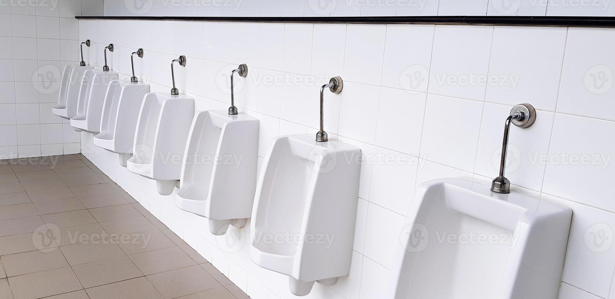 urinario blanco sobre pared blanca en baño público masculino, baño o sala de descanso. objeto, diseño de interiores, artículos sanitarios y concepto de saneamiento. foto