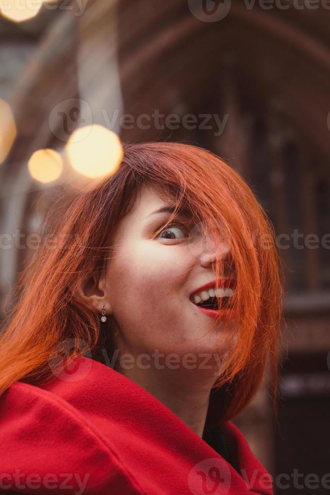 Close up excited young woman in red coat in city portrait picture photo