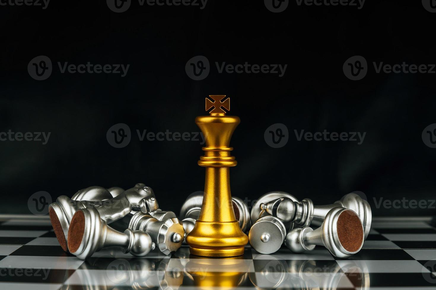 Winner. gold king surrounded with silver chess pieces on chess board game competition with copy space on dark background, chess battle, success, team leader, teamwork and business strategy concept photo