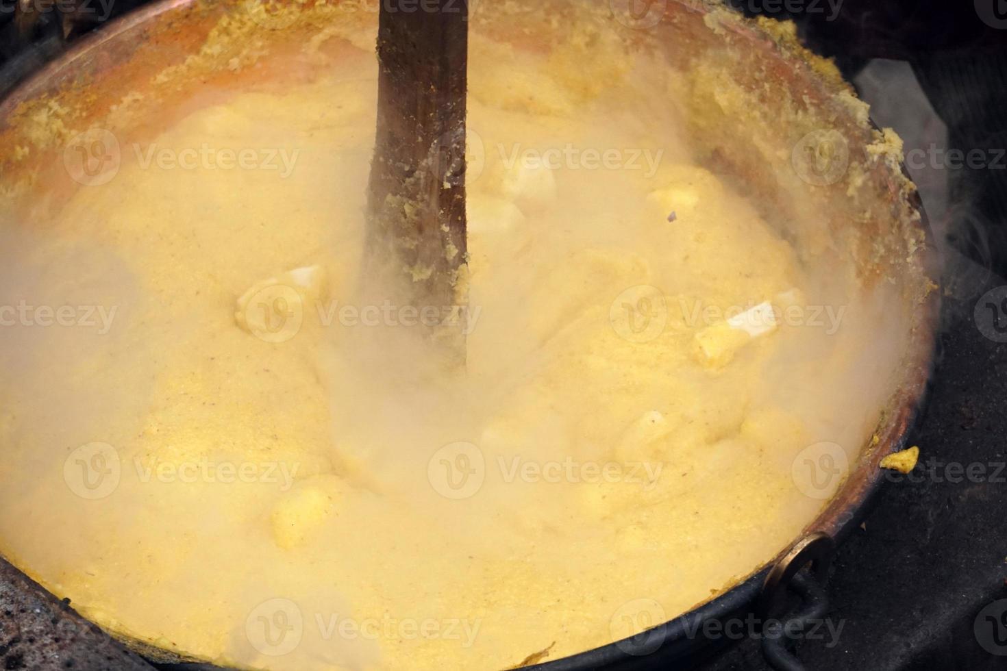 RANGO, ITALY - DECEMBER 8, 2017 - People cooking polenta traditional corn wheat meal photo