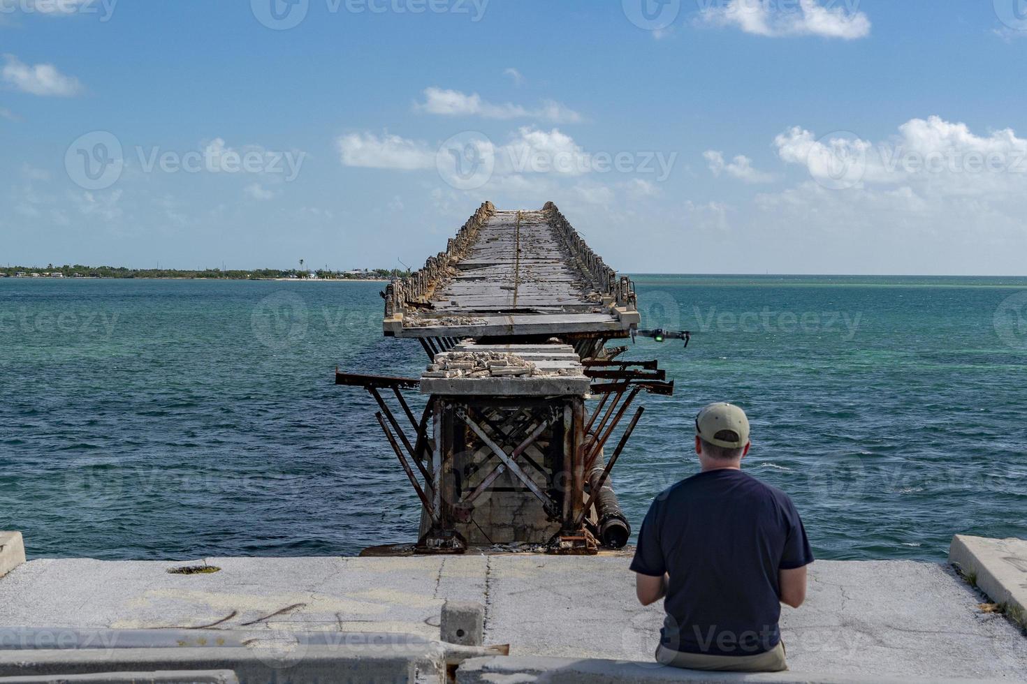 man flying a drone in damaged bridge in key west island photo