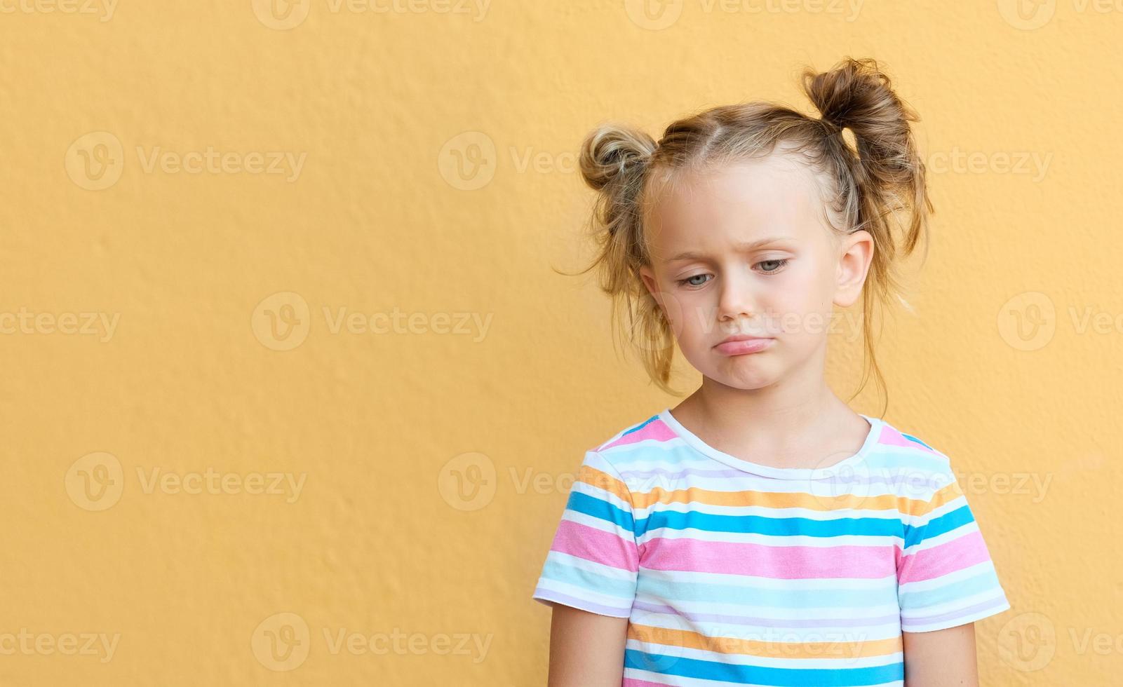 Unhappy little girl kid isolated over yellow studio background.Children negative emotions and feelings. Mock up,copy,text photo