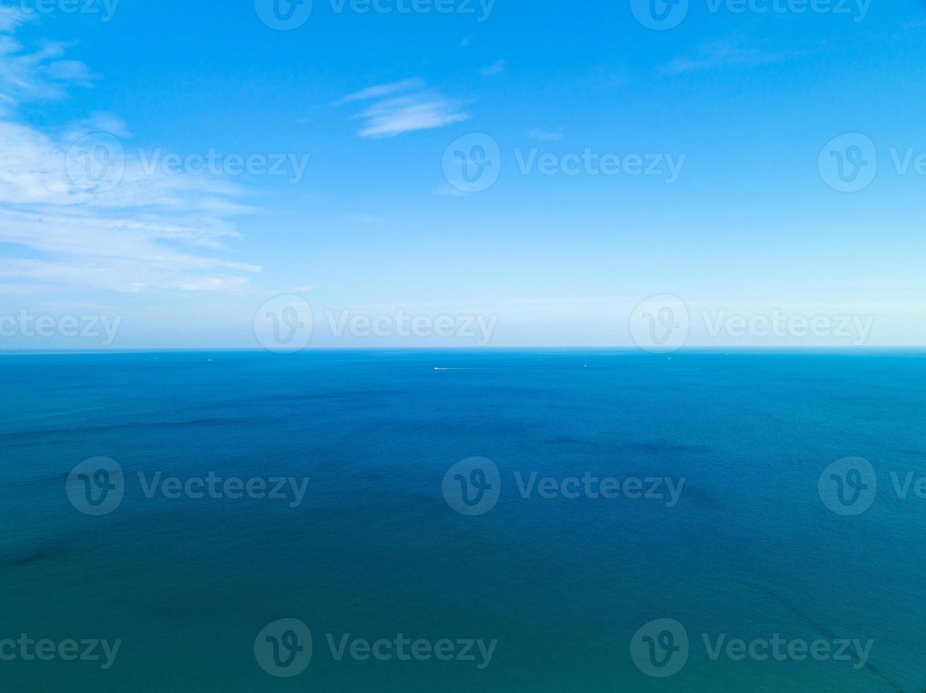 asombrosas nubes blancas con cielo azul sobre el mar tranquilo y reflejo de la luz del sol, vista aérea de la superficie del agua del océano abierto, cielo claro y nubes sobre el océano, mar vibrante con fondo de nubes foto