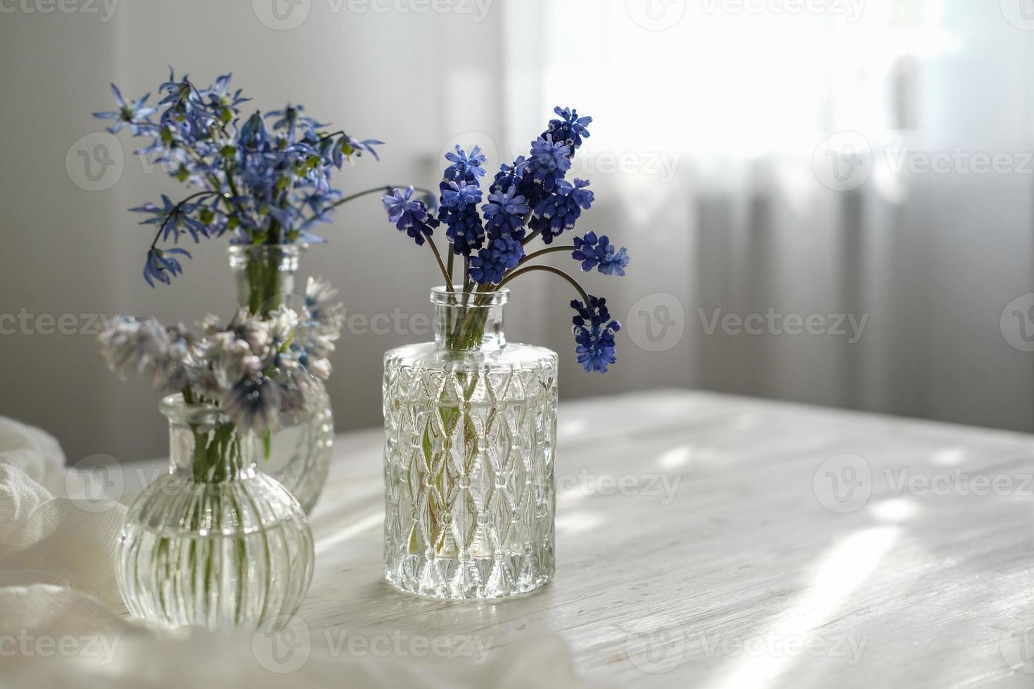 Various spring flowers in glass bottles on a table by the window in the sun. Spring still life photo