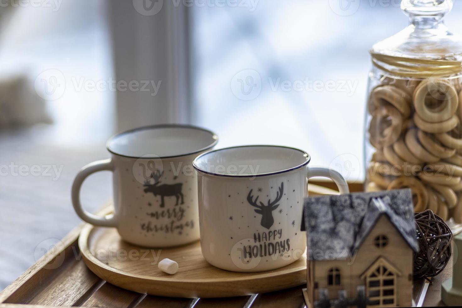 café navideño matutino con malvaviscos y adornos navideños en una mesa de bandeja junto a la ventana en el alféizar de la ventana foto