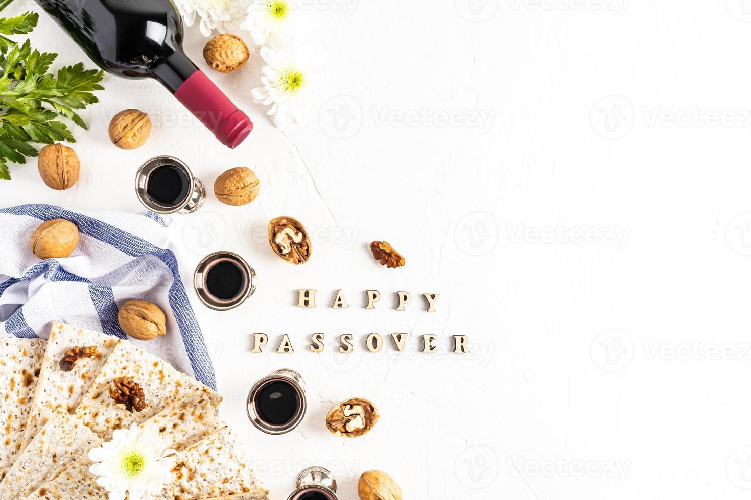 festive background of the Jewish Passover with matzah, red kosher wine and silver glasses, nuts on a white background with the text Happy Passover. photo