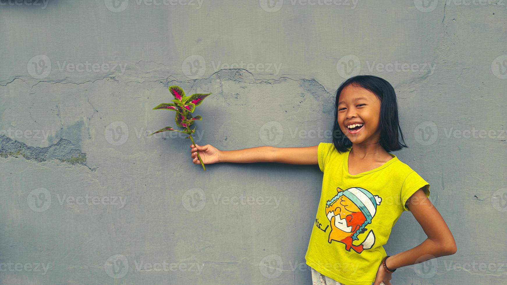 Little girl holding young plant.  Green Leaves. Ecology concept. Light color background. photo