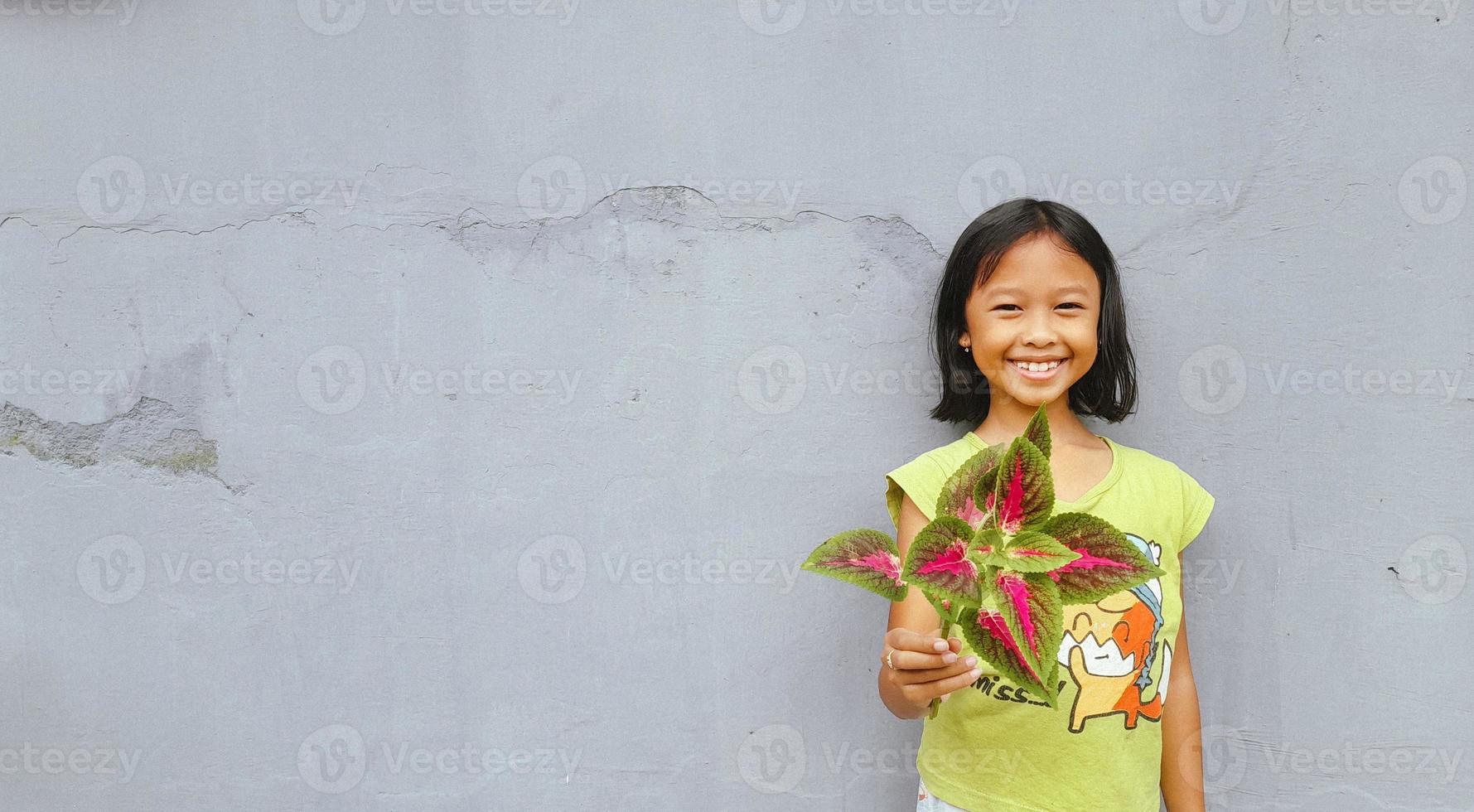 Little girl holding young plant.  Green Leaves. Ecology concept. Light color background. photo