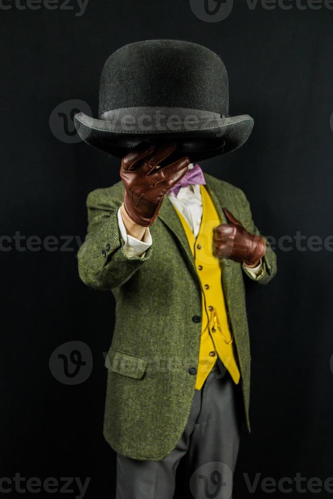 Portrait of Successful Man in Tweed Suit and Leather Gloves Holding Bowler Hat on Black Background. Retro Style and Vintage Fashion of Classic British Gentleman photo