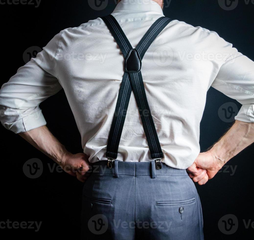 retrato de primer plano de la parte posterior de un hombre de negocios musculoso fuerte en camisa de vestir blanca y tirantes. foto