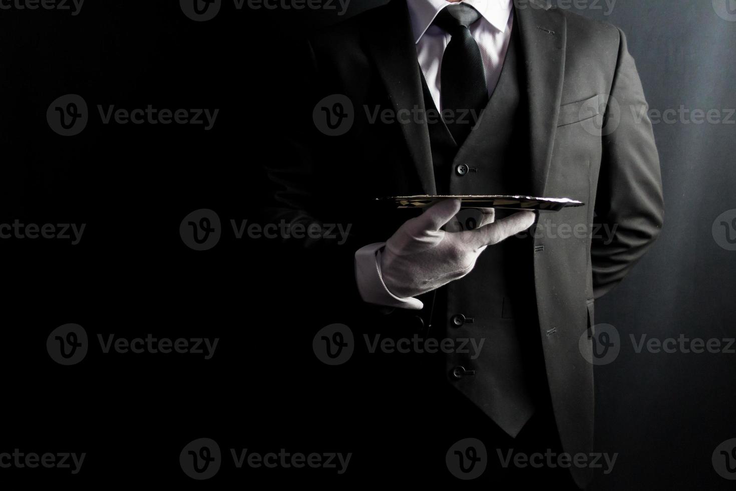 Portrait of Butler or Waiter in Dark Formal Suit and White Gloves Elegantly Holding Silver Serving Tray. Copy Space for Service Industry and Elite Hospitality. photo