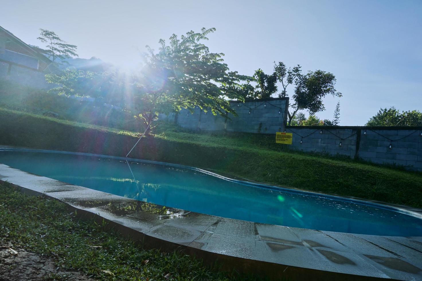 el ambiente en la piscina del patio trasero por la mañana con rayos de sol. foto