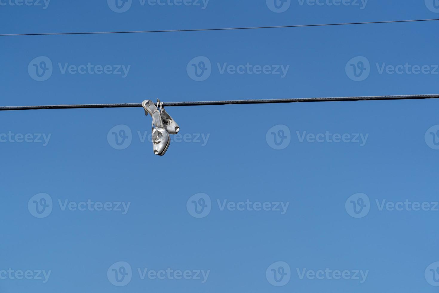 Woman female shoes hanging on wire cable photo