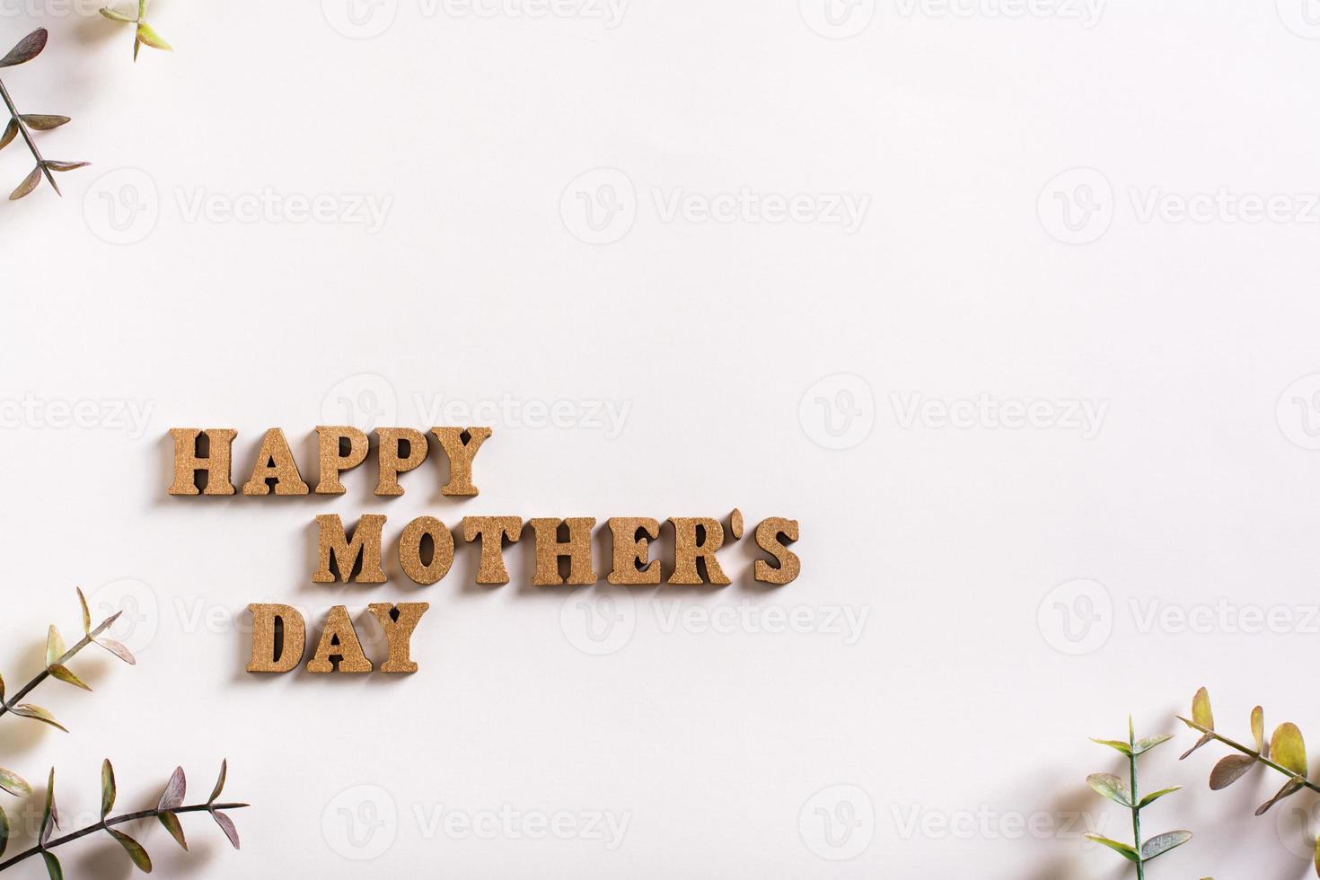 Happy mother's day. Wooden letters and eucalyptus branches on a light background. Copy space photo