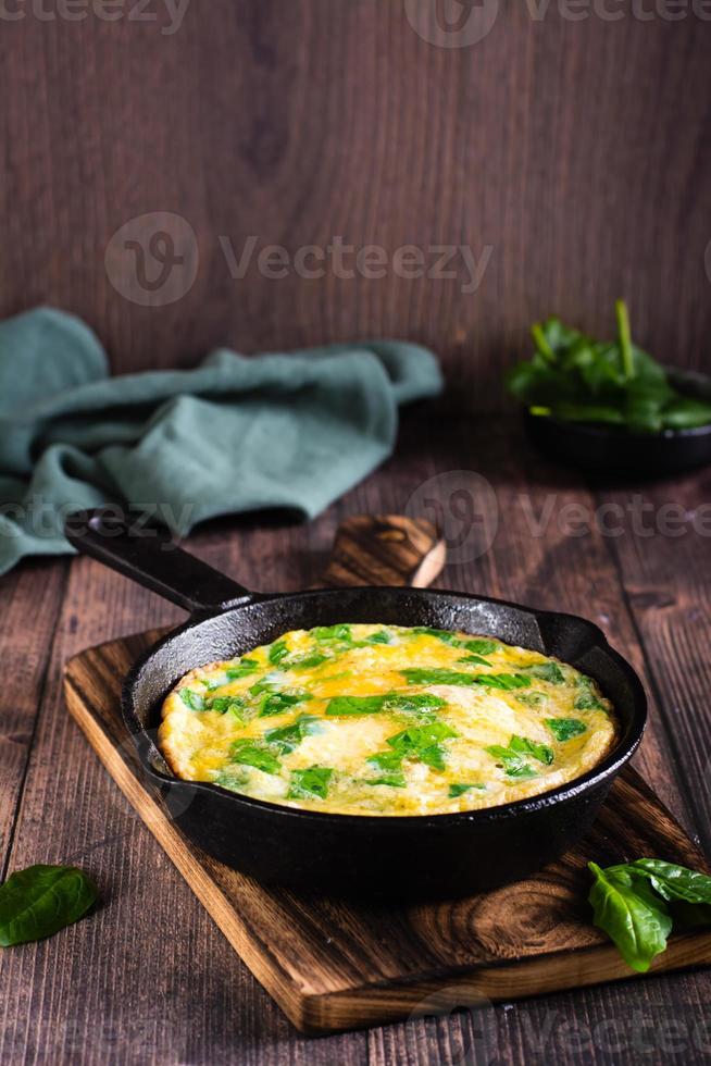 Omelet with spinach and cheese in a pan on the table. Ketogenic diet. Vertical view photo