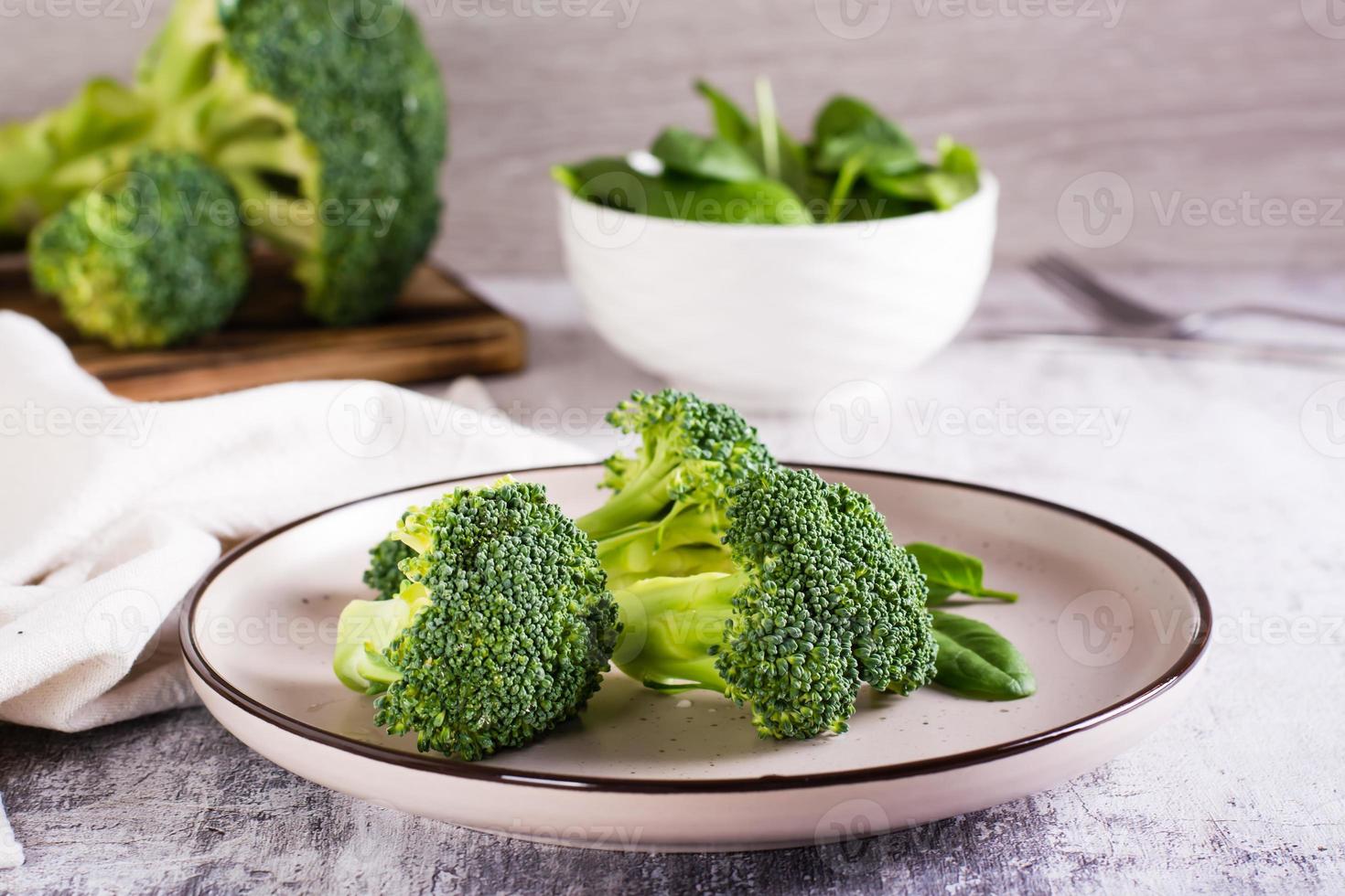 Fresh broccoli divided into inflorescences on a plate on the table. Vegetable diet. photo
